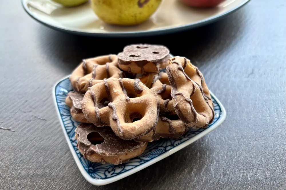 Small bowl of Reese's Dipped Pretzels in front of a plate with fruit